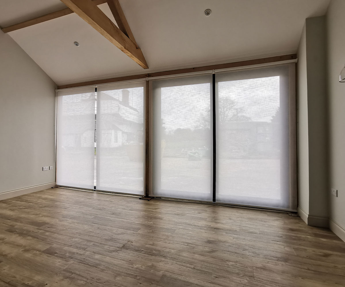Full-length sheer roller blinds in a barnhouse-style interior