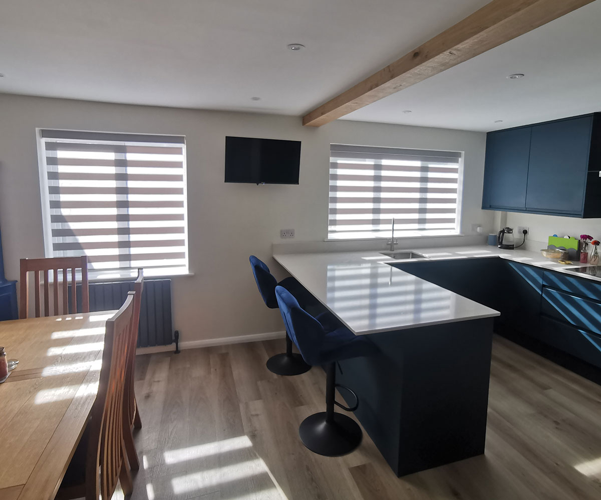 Grey vision blinds fitted in a contemporary kitchen with navy cabinetry